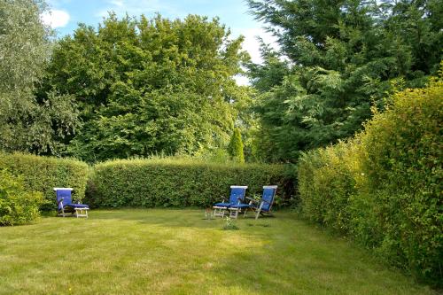 two blue chairs sitting in a yard next to a hedge at Der Charlottenhof in Ahrenshoop