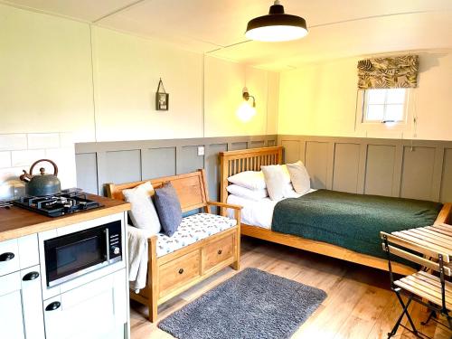 a small bedroom with a bed and a stove at Clay Bank Huts, Roseberry Shepherds Hut in Ingleby