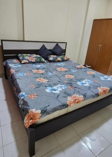 a bed with a blue comforter with flowers on it at APPLE HOME STAY in Sharjah