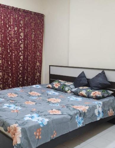 a bed with a blue comforter with flowers on it at APPLE HOME STAY in Sharjah