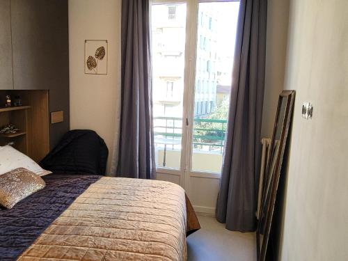 une chambre avec un lit et une grande fenêtre dans l'établissement Promenade des Anglais, à Nice