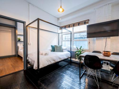 sypialnia z łóżkiem z baldachimem i biurkiem w obiekcie London Industrial 1 bedroom Apartment Camberwell Pass the Keys w Londynie