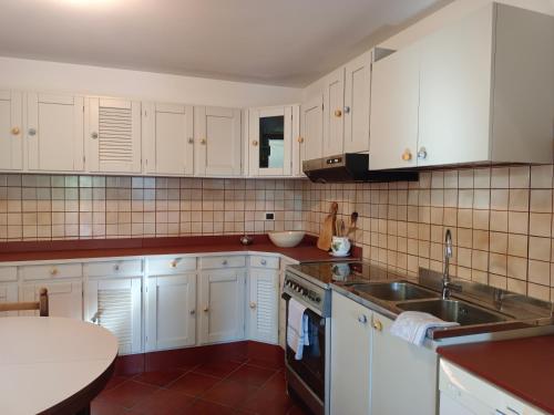 eine Küche mit weißen Schränken und einem Waschbecken in der Unterkunft La taverna di Anna in San Pietro di Feletto