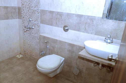 La salle de bains est pourvue de toilettes blanches et d'un lavabo. dans l'établissement Kings Resort, à Silvassa