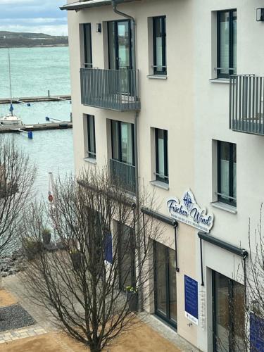 un edificio blanco con un letrero junto al agua en Frischer Wind am Hainer See Kahnsdorf, en Neukieritzsch