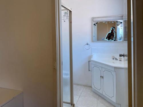 a white bathroom with a sink and a mirror at K. A hundred meters is equivalent to a tram station homestay and king bed in Melbourne