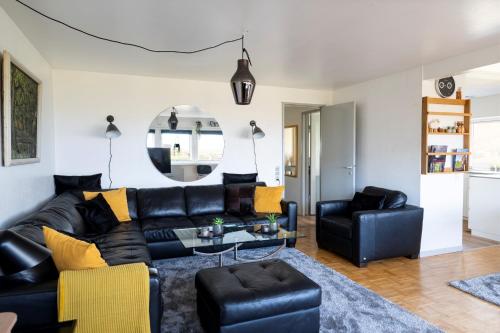 a living room with black leather furniture and a mirror at The Old Sherrif's House - Family Friendly - Beach in Sandur