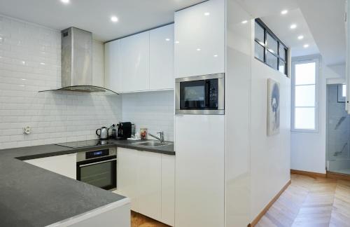 une cuisine blanche avec un évier et un micro-ondes dans l'établissement Elysée/Fg St Honoré- 2 piéces de luxe, à Paris