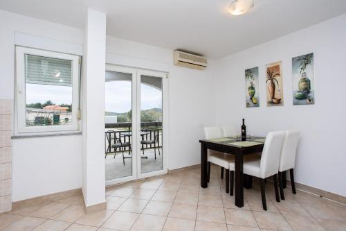 a dining room with a table and chairs and a balcony at Sunset Apartman Ana in Zaboric