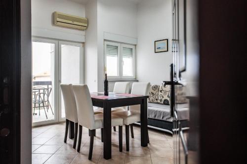 a dining room with a table and white chairs at Sunset Apartman Ana in Zaboric
