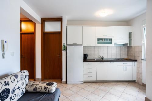 a kitchen with white cabinets and a white refrigerator at Sunset Apartman Ana in Zaboric