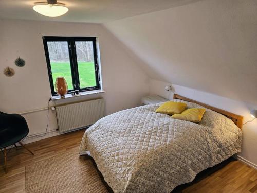 Un dormitorio con una cama con almohadas amarillas y una ventana en Privat lejlighed på landejendommen Frederiks-Eg, en Herlufmagle