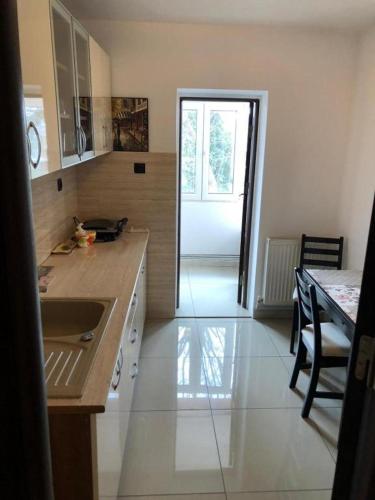 a kitchen with a sink and a table with a counter at Page2 Apartament in Târgovişte