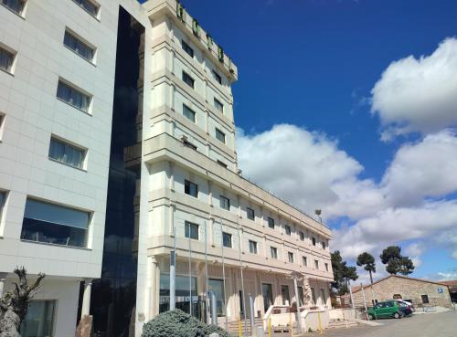 a tall white building with a blue sky at Hotel Sercotel Cuatro Postes in Avila