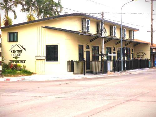 a white building with a black fence next to a street at Kenton House in Savannakhet