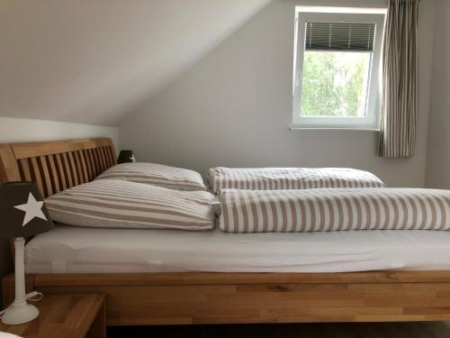 a bed with striped sheets and a window in a room at Haus Hyggelig direkt am Großen Zechliner See in Rheinsberg