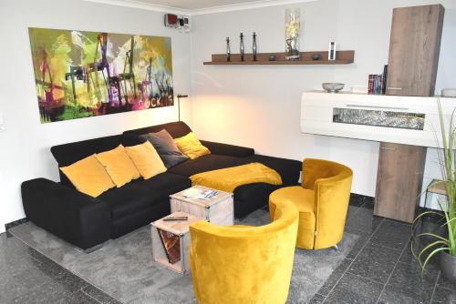 - un salon avec un canapé noir et des fauteuils jaunes dans l'établissement Ostseeallee 4 Ferienwohnung Nr 01, à Niendorf