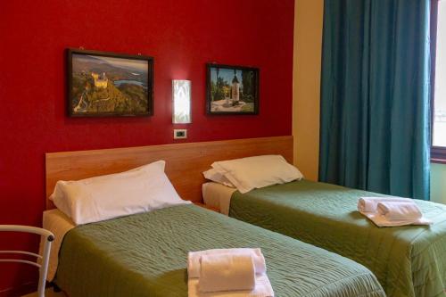 two beds in a room with red walls at Hotel Erbaluce in Caluso