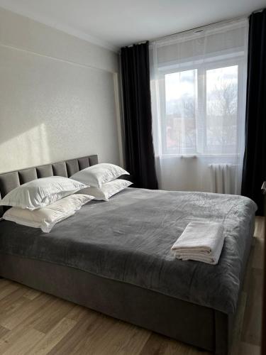 - une chambre avec un grand lit et une fenêtre dans l'établissement Apartment on Protozanova 21, à Öskemen
