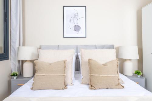 a bedroom with a white bed with pillows and two lamps at Appartements Rayonnants aux Sources in Vieux Kouba