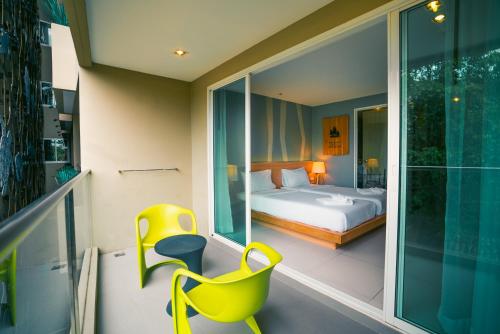 um quarto com uma cama e uma cadeira amarela numa varanda em Mad Monkey Phuket em Patong Beach