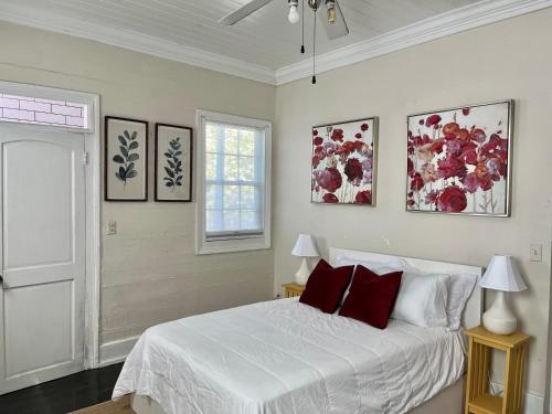 um quarto com uma cama branca e almofadas vermelhas em Downtown Nassau Oasis Unit 2 em Nassau
