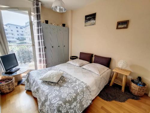 - une chambre avec un lit, une télévision et une fenêtre dans l'établissement Les Thermes d'Evian - Appartement de vacances, à Évian-les-Bains