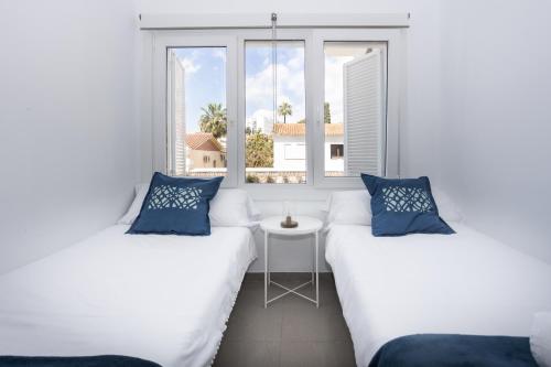 two beds in a room with a window at San Miguel 34 Rooms in Málaga