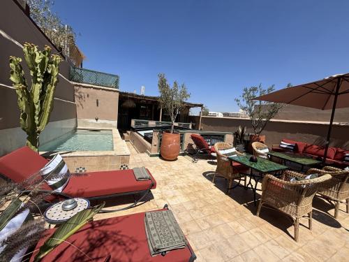 a patio with tables and chairs and a swimming pool at Riad Dar Nakous in Marrakesh