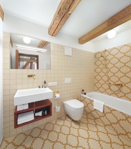 a bathroom with a sink and a toilet and a tub at Engelwirt Hotel & Apartments in Berching