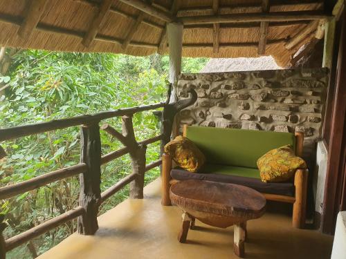 a room with a green couch and a stool at Pumba Safari Cottages in Busonga