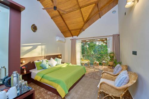 een slaapkamer met een groen bed en een stoel bij PANCHAVADI FARM STAY in Thekkady