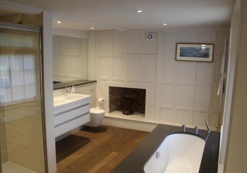 a bathroom with a bath tub and a fireplace at West Pallant Georgian Townhouse in City Centre with Courtyards, BBQ & Log Burners - Dogs Welcome! - Chichester Holiday Properties in Chichester