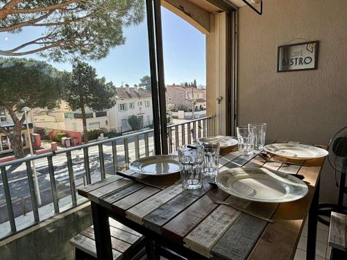 une table en bois avec des assiettes et des verres sur un balcon dans l'établissement Studio cabine à 400m de la mer avec piscines, parking privé et loggia - Argelès-sur-Mer - FR-1-225-768, à Argelès-sur-Mer