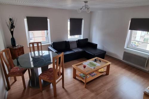 un salon avec un canapé noir et une table dans l'établissement Schirmeck centre appartement au pied du château, à Schirmeck