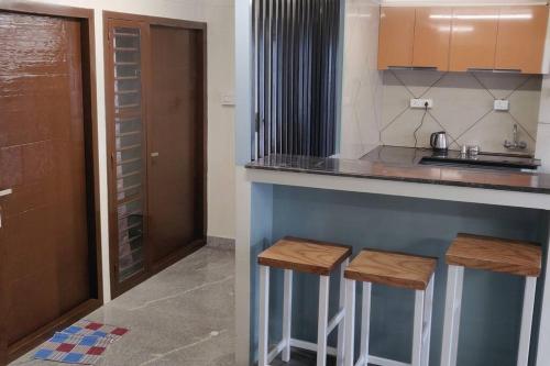 a kitchen with a counter with two stools in it at All Seasons, luxury villa in Kotagiri
