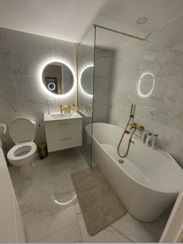 La salle de bains blanche est pourvue d'une baignoire et de toilettes. dans l'établissement Petite Maison à la Loubiere avec jardin, clim et parking, à Toulon