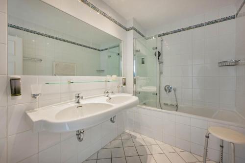 ein weißes Bad mit einem Waschbecken und einer Dusche in der Unterkunft Villa Hohe Düne 05 in Heringsdorf