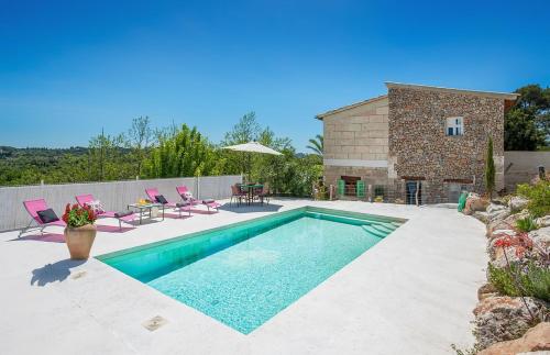 een zwembad met roze stoelen en een huis bij Sa Fontasa in Moscari