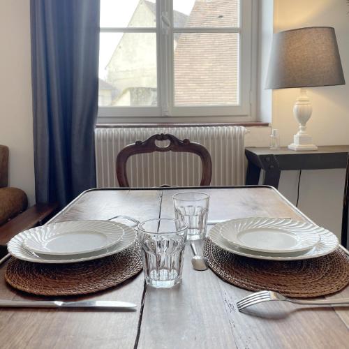 a wooden table with plates and glasses on it at Appartements 4 vents by La Boîte En Plus in Senlis