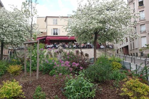 um jardim com flores e uma árvore numa cidade em Excellent Appart totalement rénové em Paris