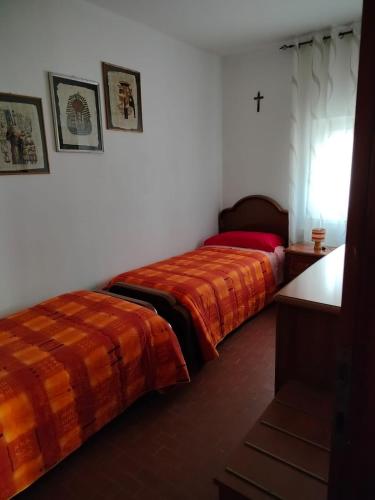 2 Betten in einem Zimmer mit einem Kreuz an der Wand in der Unterkunft Appartamento al Lago in Levico Terme