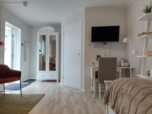 a bedroom with a bed and a desk and a television at B&B Villa Orion in Sölvesborg