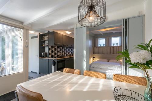 a kitchen and dining room with a table and a bed at Duinland 110 - Sint Maartenszee in Sint Maartensvlotbrug