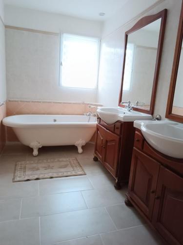 une salle de bain avec deux lavabos, une baignoire et un miroir dans l'établissement Les Grillons, à Sainte-Maxime