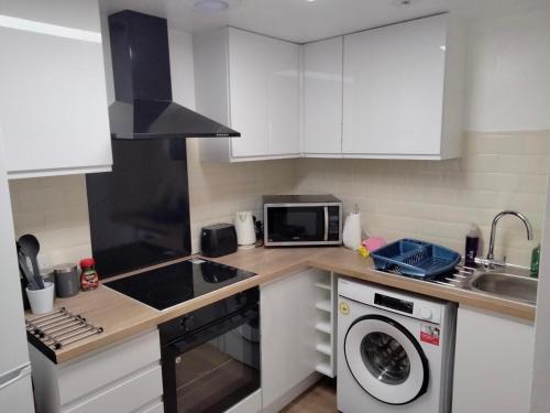 a kitchen with white cabinets and a washing machine at Flat 1, 106 Belgrave Gate in Leicester