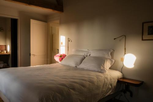 Schlafzimmer mit einem Bett mit weißer Bettwäsche und Kissen in der Unterkunft Petit Chateau Vercourt in Vercourt