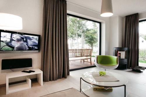 een woonkamer met een tv en een groene stoel bij die Strandhäuser - Strandläufer in Ostseebad Sellin
