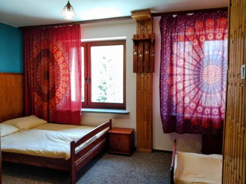 sypialnia z 2 łóżkami i czerwonymi zasłonami w obiekcie Bieszczadzka Legenda w Wetlinie