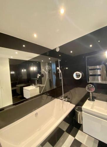 La salle de bains est pourvue d'une grande baignoire blanche et d'un miroir. dans l'établissement Luxury appartment 10 mn from Champs-Elysées, à Neuilly-sur-Seine